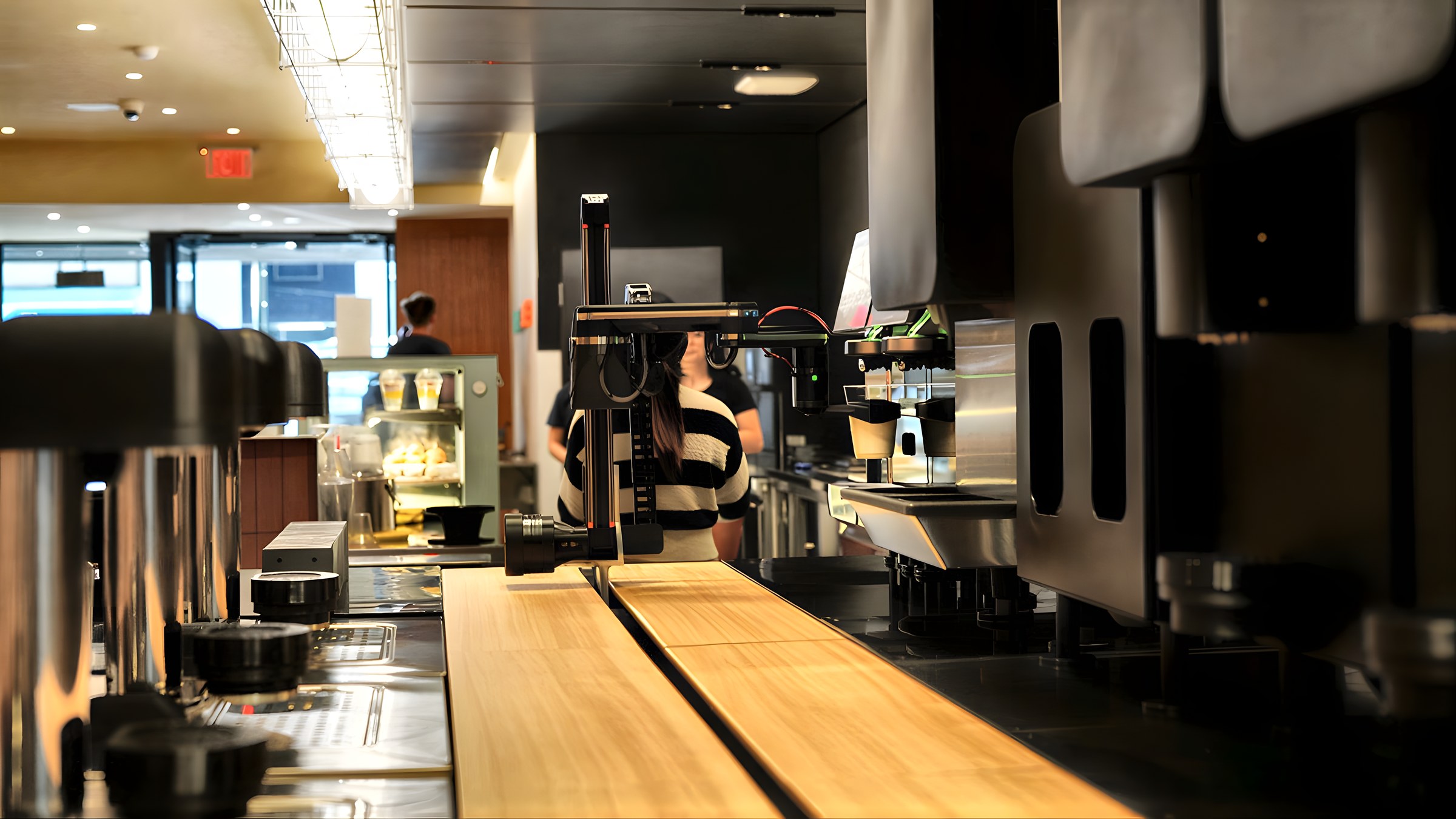 A Yummy Future barista works the counter beside the robot arm
