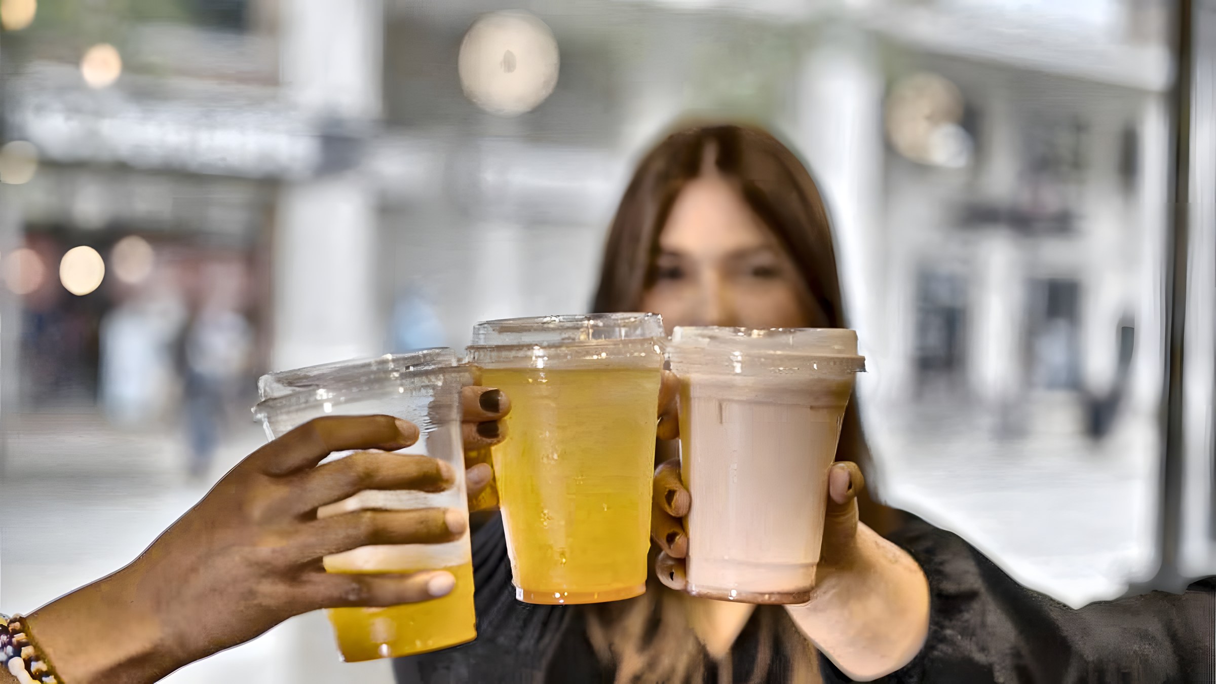 Three friends toasting with Yummy Future drinks outside a store