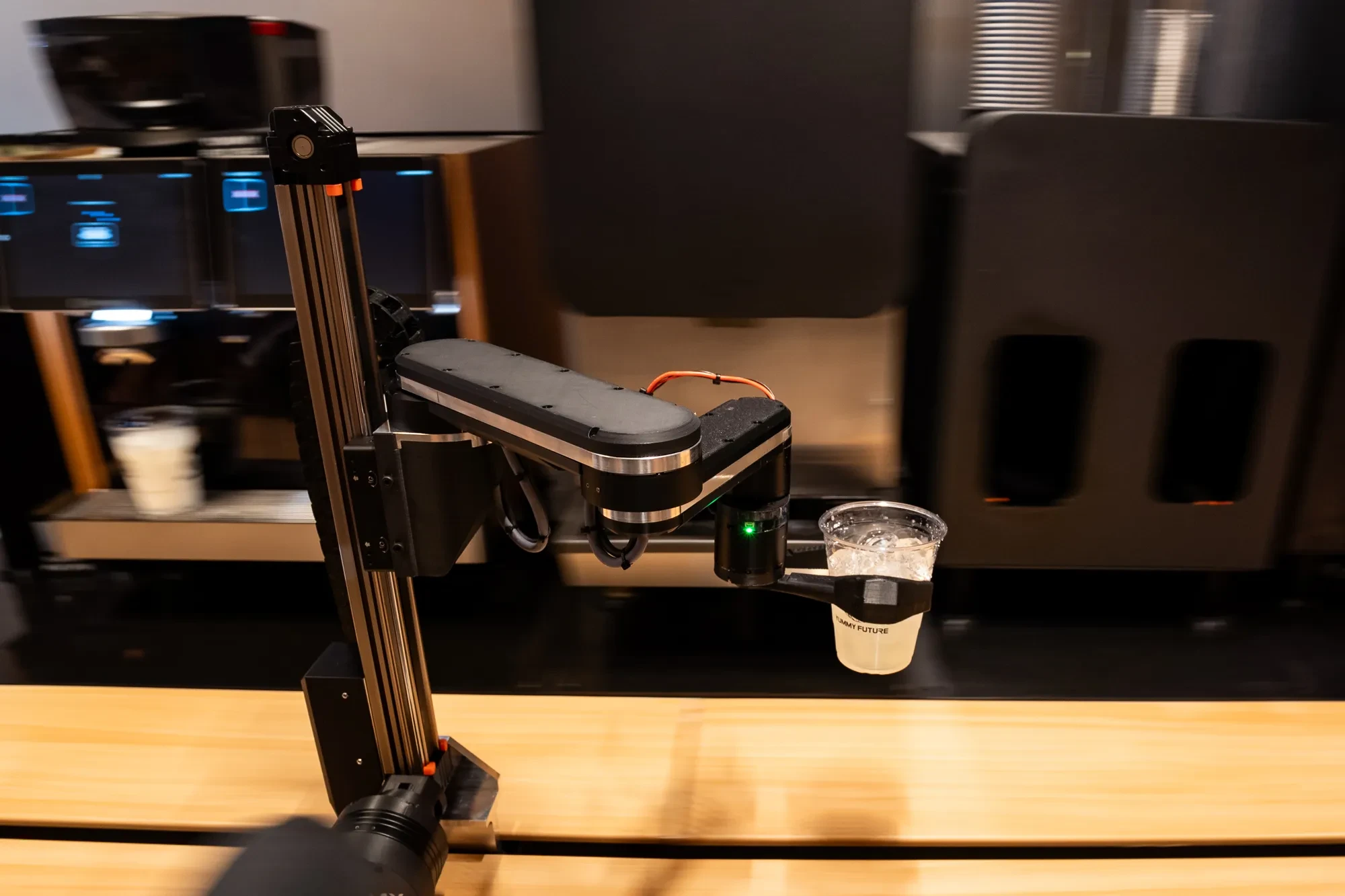 The robot arm lifting an iced drink at the bar